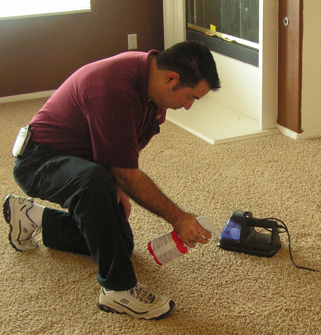 A man kneeling down and working on the floor with a tool